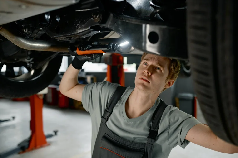 Mechanic inspecting car suspension and undercarriage in Perth